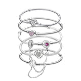 Stack of silver bracelets with heart-shaped charms on a white background