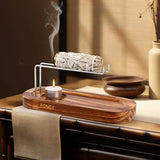 Wooden incense burner with a burning candle and smoldering sage on a wooden surface.