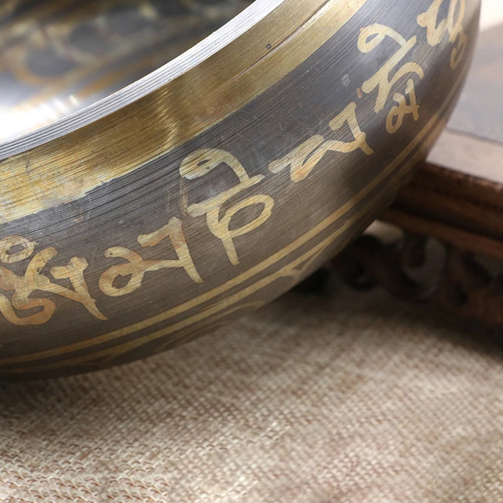 Close-up of a metal bowl with engraved text on a textured surface