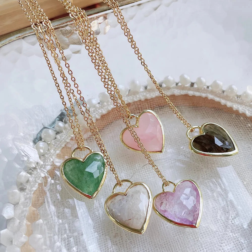 Gold necklaces with heart-shaped gemstones on a textured surface