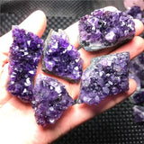 Hand holding purple crystal formations against a blurred background