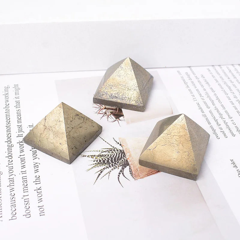 Three geometric stone pyramids on a white surface with text and a plant.