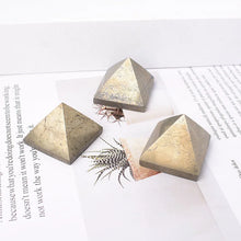Three geometric stone pyramids on a white surface with text and a plant.