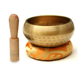Tibetan singing bowl with wooden striker on a white background