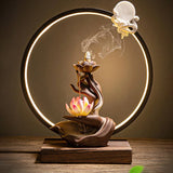 Decorative incense burner with lotus design and circular light fixture on a wooden base.