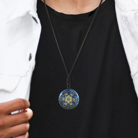 Person wearing a black shirt with a blue and gold pendant necklace.