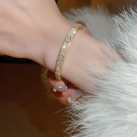 Gold bracelet with diamonds on a wrist against a soft background