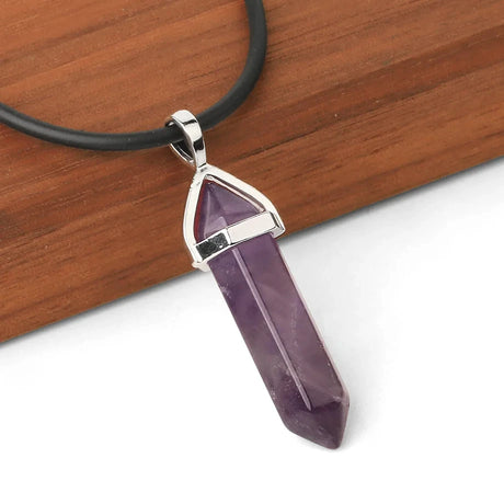 Amethyst crystal pendant on a black cord against a wooden background