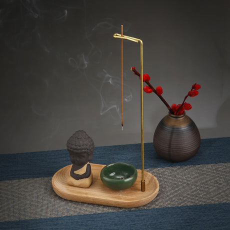Incense burner with Buddha statue, bowl, and vase on a textured surface with dark background
