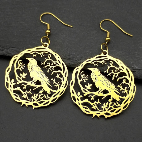 Gold bird earrings on a dark stone background