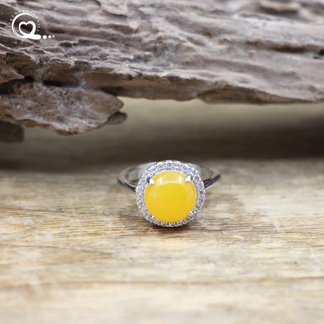 Ring with a yellow gemstone and silver border on a wooden surface