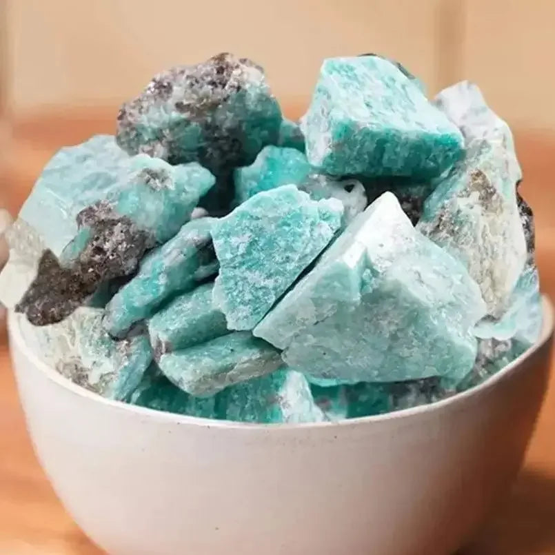 Turquoise crystal stones in a white bowl on a wooden surface