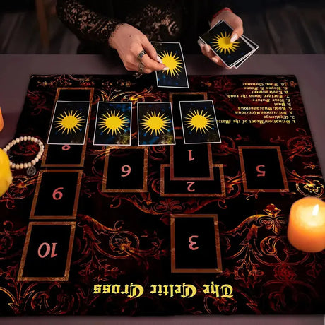 Tarot cards arranged on a dark cloth with candles and a glass of water.