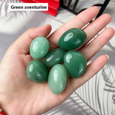 Hand holding green aventurine stones with a blurred background