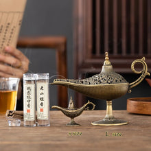 Decorative incense burner with two bottles of incense on a wooden table.