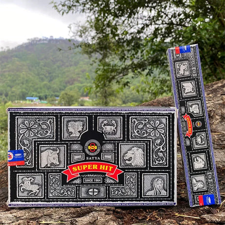 Two Satya Super Hit incense boxes on a natural background with trees and mountains.