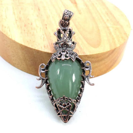 Pendant with green stone and intricate metalwork on a white background