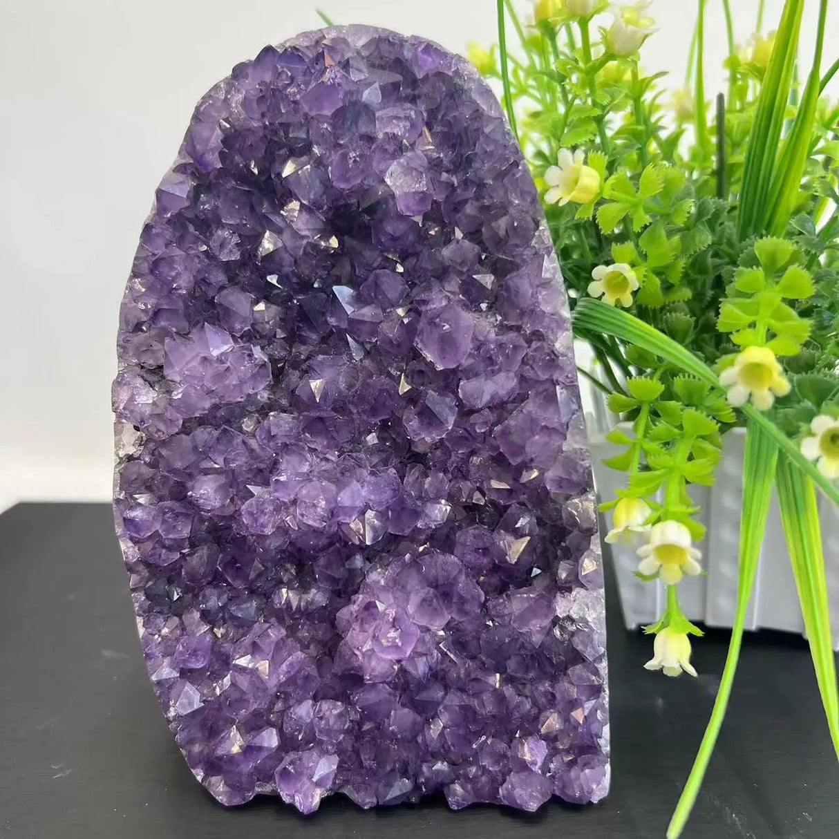 Amethyst crystal formation with green plants in the background