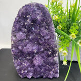 Amethyst crystal formation with green plants in the background