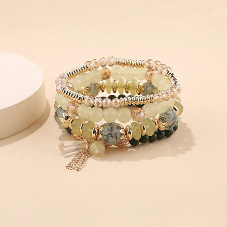 Stack of beaded bracelets with gold accents on a beige background