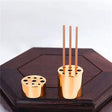 Gold incense holder with three sticks on a wooden surface