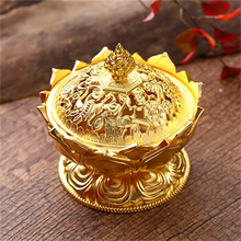 Gold decorative item with intricate designs on a wooden surface