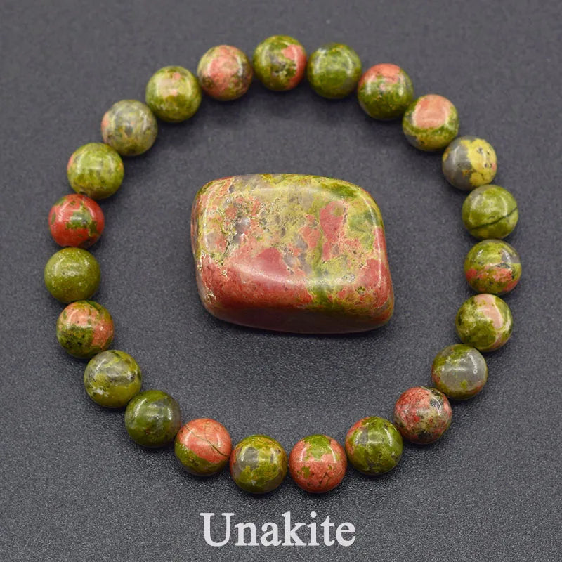 Unakite stone with a bracelet made of unakite beads on a dark background