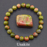 Unakite stone with a bracelet made of unakite beads on a dark background