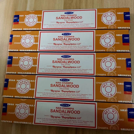 Multiple boxes of Nag Champa Sandalwood incense on a wooden surface