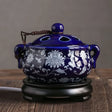 Blue ceramic incense burner with white floral patterns on a wooden surface.