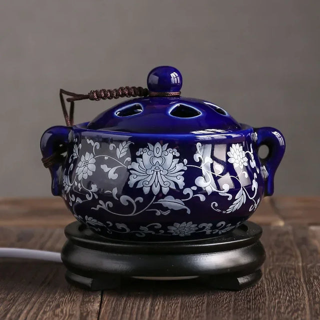 Blue ceramic incense burner with white floral patterns on a wooden surface.