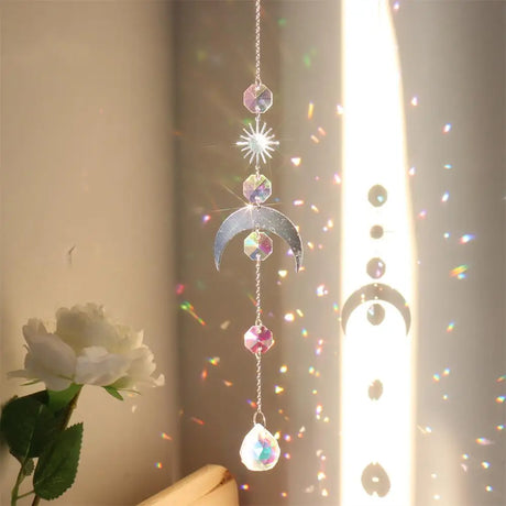 Decorative hanging crystal with rainbow, next to a white rose.
