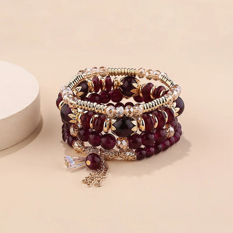 Stack of burgundy beaded bracelets with gold accents on a beige background