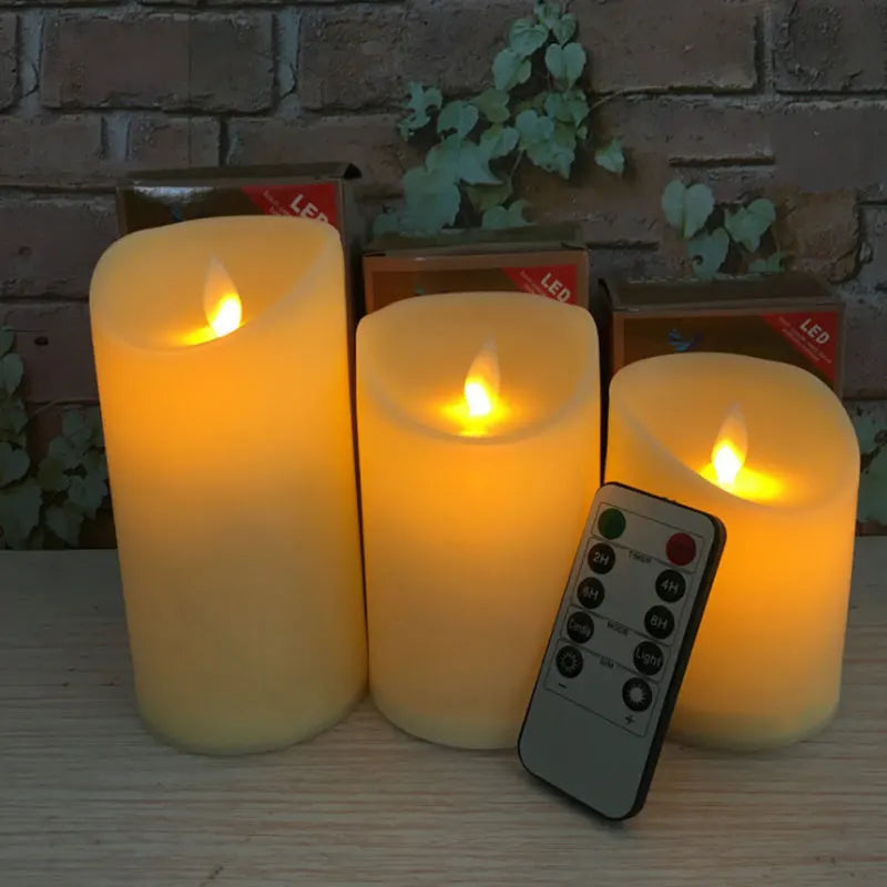 Set of three LED candles with a remote control on a wooden surface.