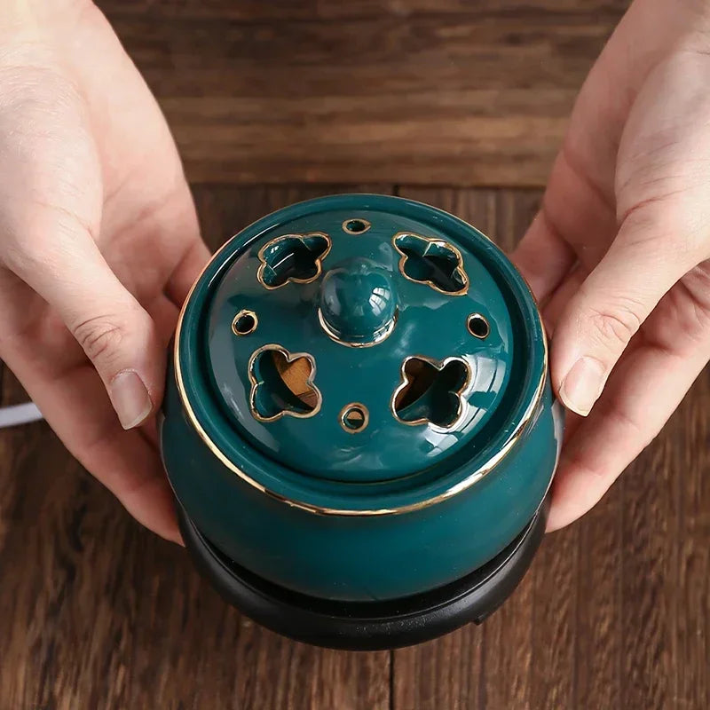 Teal ceramic incense burner with decorative top held by two hands on a wooden surface