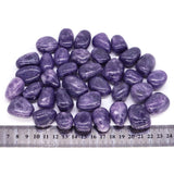 Purple stones with a ruler for size reference on a white background