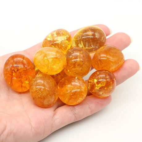 Hand holding a handful of orange marbles on a white background