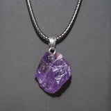 Purple crystal pendant on a silver chain against a gray background