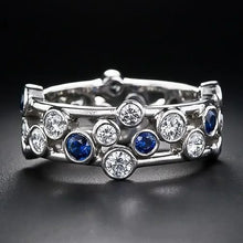 Silver ring with blue and clear gemstones on a black background