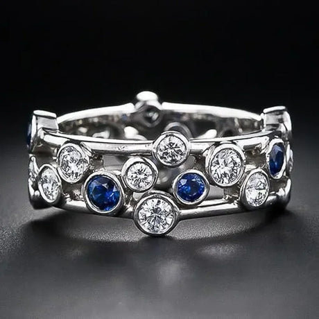 Silver ring with blue and clear gemstones on a black background