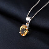 Silver pendant with a yellow gemstone on a dark fabric background