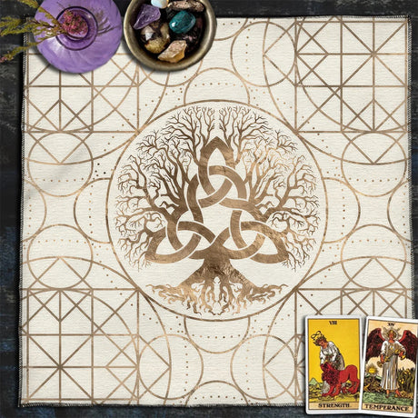 Decorative mat with tree of life design, tarot cards, and crystals on a dark surface.