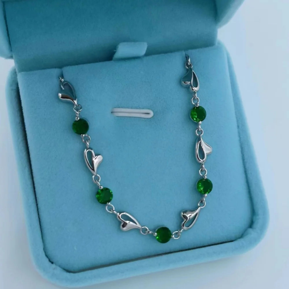 Silver bracelet with green beads on a blue jewelry box