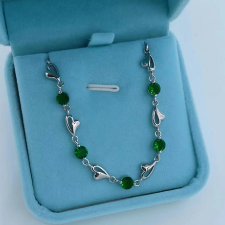 Silver bracelet with green beads on a blue jewelry box