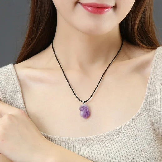 Woman wearing a necklace with a purple pendant against a neutral background