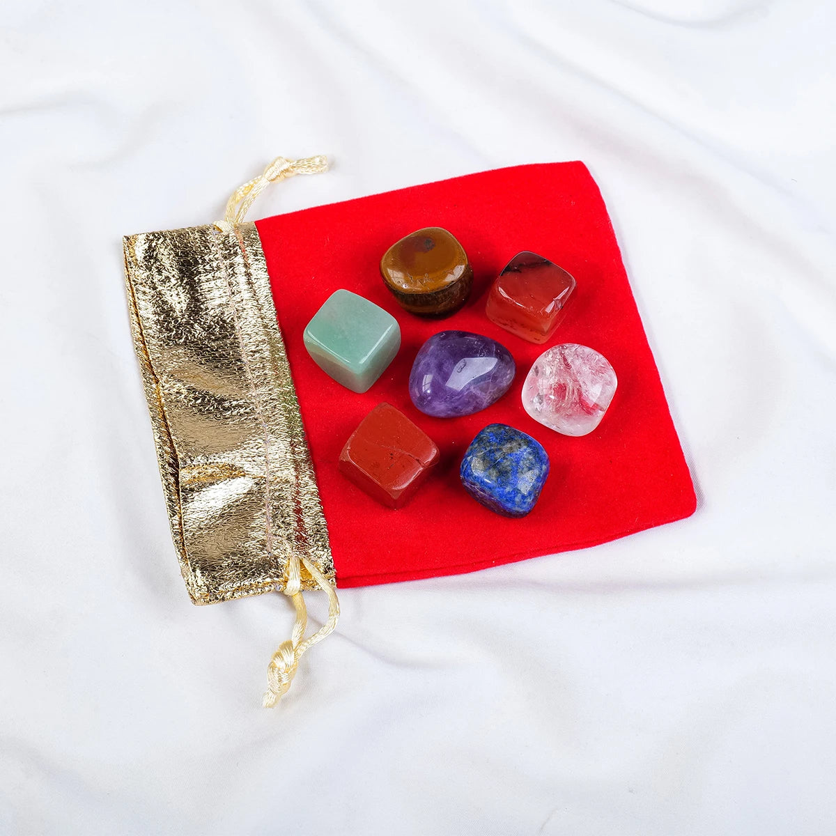 Set of colorful crystals on a red cloth with a gold pouch on a white background