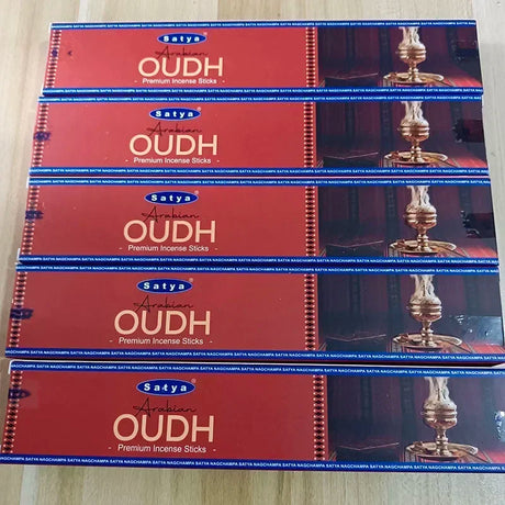 Multiple packages of Satya Arabian Oudh Premium Incense Sticks on a light wooden surface.