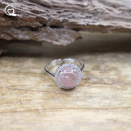 Silver ring with a pink gemstone on a wooden surface
