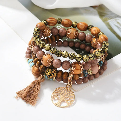 Stack of wooden beaded bracelets with tassel and tree pendant on a white surface