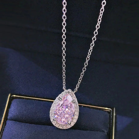 Pink diamond necklace on a dark blue cushion with a black background